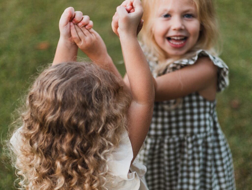 Photo of girls playing while holding hands and smiling. 