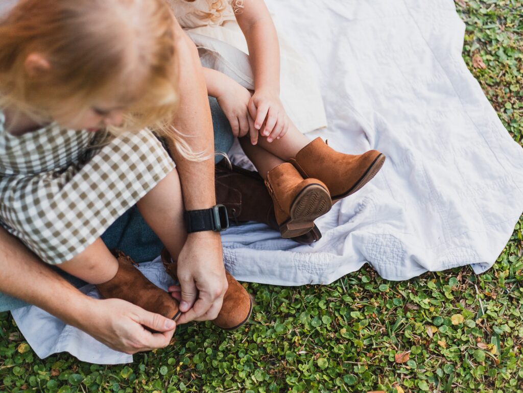 Detail shot of children's wearing boots while sitting on a blanket. 