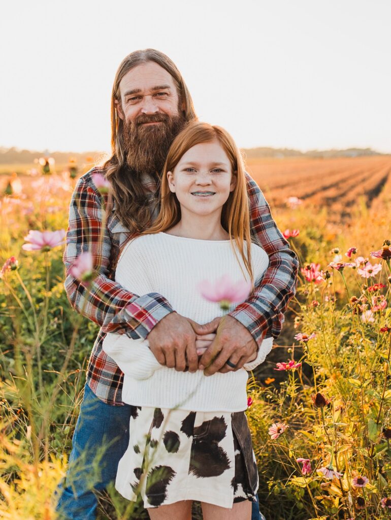 Family photo of father and daughter at sunset standing in a field of flowers at Parker Flower Farms 