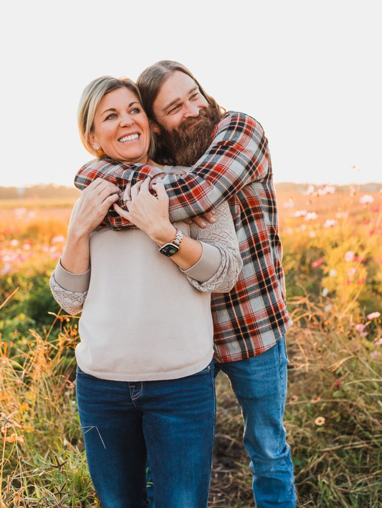Husband and wife embrace in field of flowers at parker flower farms in Elkton, Florida
