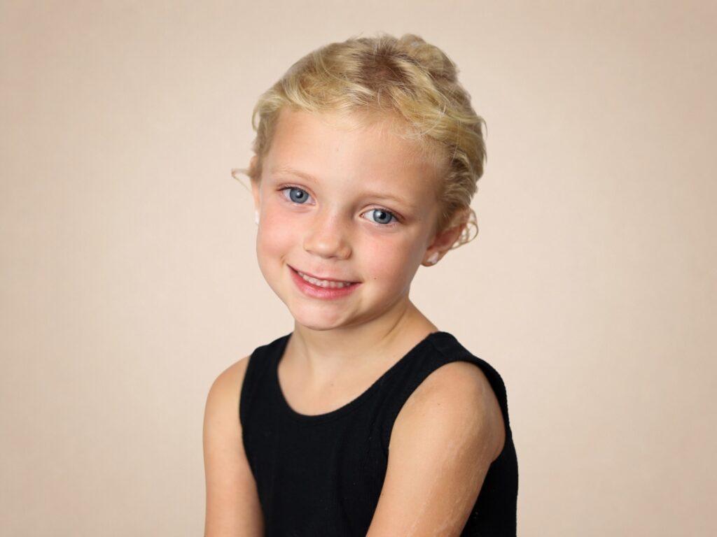 School portrait of elementary student smiling against a beige background