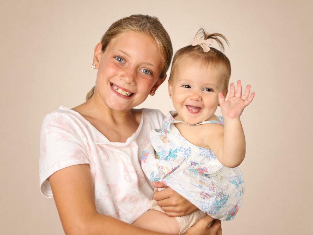 Sibling portrait of a big sister holding her baby sister during picture day in Jacksonville.